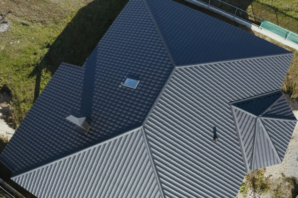 Aerial view of a house featuring a metal roof, illustrating the importance of how often to replace roof materials.